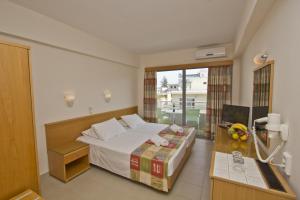 a bedroom with a bed and a desk and a window at Nafsika Hotel in Rhodes Town