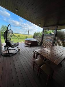 a deck with a bench and a chair and a table at Domo Vila in Druskininkai