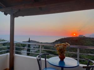 a vase on a table on a balcony with a sunset at Itaka Hotel Lukova in Lukovë
