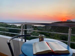 a table with two books and a cup of coffee on a balcony at Itaka Hotel Lukova in Lukovë