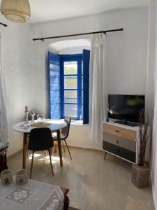 een woonkamer met een tafel, een tv en een raam bij Veneto's Garden in Kardhamili