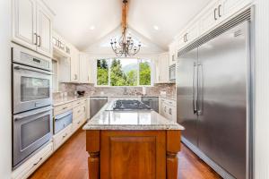Una cocina con gabinetes blancos y un refrigerador de acero inoxidable. en Snowy Court, en Girdwood