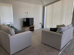 a living room with two couches and a flat screen tv at Beach Base Lodge, Padstow Cornwall in Padstow