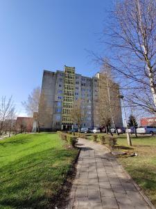 a tall building in a park with a sidewalk at Prie Masčio ežero in Telšiai