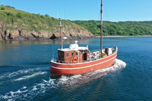 una barca rossa in acqua su un fiume di Unique Boat Accomodation - Bornholm a Hasle