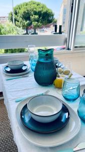 une table avec des plaques bleues et un vase bleu sur elle dans l'établissement Flore, au Grau-du-Roi 12 autres photos