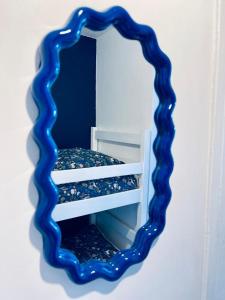 un miroir avec un cadre bleu sur un mur dans l'établissement Flore, au Grau-du-Roi