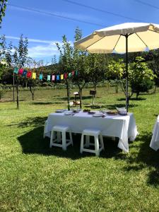 uma mesa branca com cadeiras e um guarda-sol num campo em Casa dos Avós em Póvoa de Lanhoso