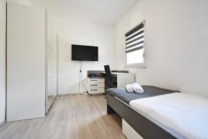 a white bedroom with a bed and a television at Apartman Lukas in Rabac
