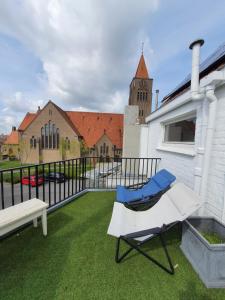 un balcón con una silla, un banco y una iglesia en Stijlvolle vakantiewoning Den Baigneur aan zee en Knokke-Heist