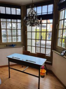 a table in a room with windows and a chandelier at Stijlvolle vakantiewoning Den Baigneur aan zee in Knokke-Heist