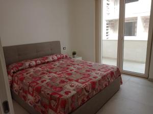 Schlafzimmer mit einem Bett mit einer roten Bettdecke in der Unterkunft Gelsimori Apartments in Otranto
