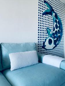 um sofá azul com uma almofada e um peixe na parede em Flore em Le Grau-du-Roi