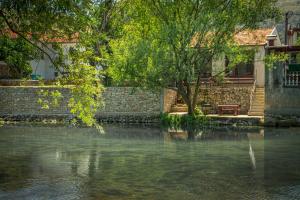 un cuerpo de agua junto a un edificio y un árbol en RiverView Buna - Mostar, en Buna