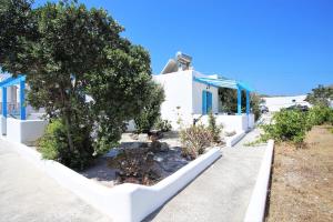 a garden in front of a white building with trees at Alice Maisonette & Studios in Adamantas