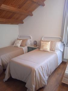 two beds in a room with white walls and wooden floors at Albergue de peregrinos Santa Marina in Molinaseca