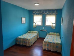 um quarto azul com duas camas e duas janelas em casa a 50 metros de playa con piscina cubierta em Liencres