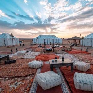 a desert encampment with tables and pillows and tents at Zagora Luxury Camp in Zagora