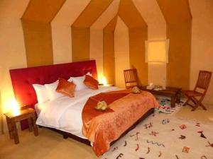 a bedroom with a large bed with a red headboard at Zagora Luxury Camp in Zagora