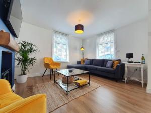 ein Wohnzimmer mit einem blauen Sofa und einem Tisch in der Unterkunft Blue Horizon Holiday Cottage - 4 Minute Walk to the Beach in Weymouth + 6 Fotos