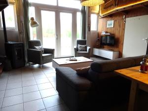 een woonkamer met een bank en stoelen en een tv bij B&B Verwoldsehof 'Op de deel' in Laren