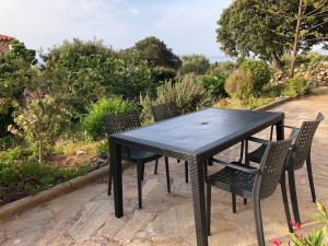 une table noire avec quatre chaises assises autour dans l'établissement Appartement rez de villa, à LʼÎle-Rousse