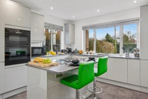 a kitchen with white cabinets and green chairs at Butterfly House - Luxury 2 Bedroom Property in Kettering