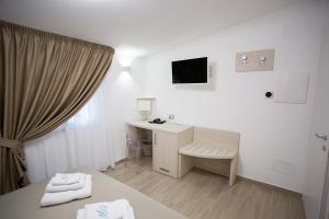 a white room with a desk and a television at Miramare Castellabate Resort in Santa Maria di Castellabate