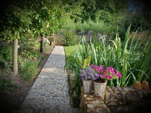 a garden with flowers in buckets and a brick path at Gastenkamer Klein Geluk in Bruges