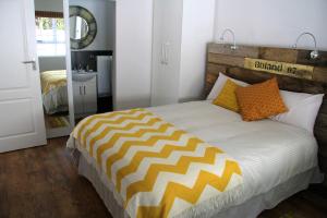 - une chambre dotée d'un grand lit avec des oreillers orange et jaune dans l'établissement Lazy Days Apartments - Cape Town, au Cap
