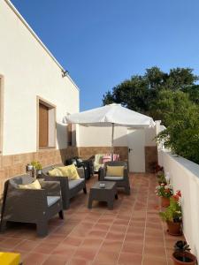 un patio al aire libre con sofás y sombrilla en Alojamientos Tía María, en Fernán Pérez