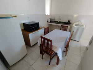 La cuisine est équipée d'une table, de chaises et d'un réfrigérateur. dans l'établissement Apartamento da Rosi, à Resende