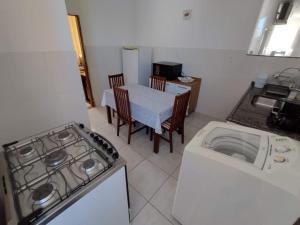 Il comprend une cuisine équipée d'une cuisinière et d'une table avec des chaises. dans l'établissement Apartamento da Rosi, à Resende