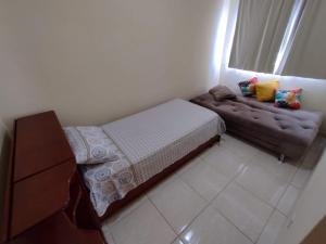 ein kleines Schlafzimmer mit einem Bett und einem Sofa in der Unterkunft Apartamento da Rosi in Resende