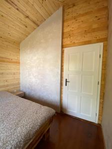 a bedroom with a bed and a white door at Cabana DEBORAH , Fardea lacu Surduc in Fîrdea