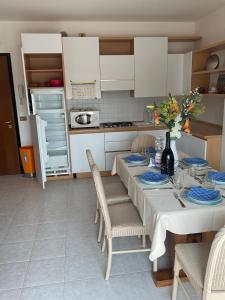 una cocina con mesa y sillas y una cocina con armarios blancos. en Bolognese Apart-Hotel 3 Stars , with Sea view, with Garage and free bicycles, en Caorle