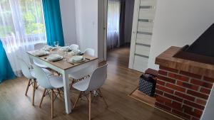 a dining room table with white chairs and a table at Domek Zacisze in Laskowa +7 photos