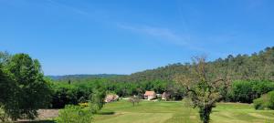 a field with a house in the middle of a forest at La Grange, Le Domaine de Brugal in Carsac-Aillac
