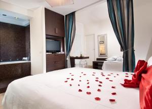 リッチョーネにあるHotel La Cappuccinaの白いベッドに赤いバラが飾られたベッドルーム1室