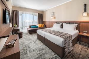 een hotelkamer met een groot bed en een bank bij Hotel Alba - All inclusive in Sunny Beach
