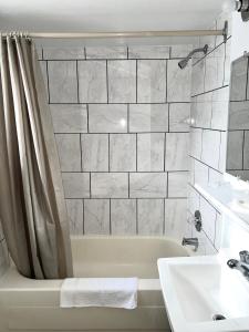 a white bathroom with a tub and a sink at Fairway Inn by the Falls in Niagara Falls