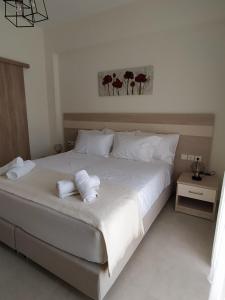 a bedroom with a white bed with towels on it at Chrysanthe's Apartments No2 in Poros