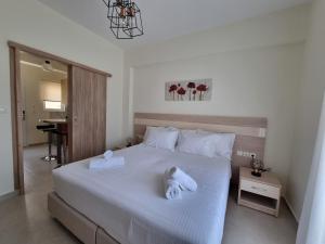 ein Schlafzimmer mit einem großen weißen Bett mit Handtüchern darauf in der Unterkunft Chrysanthe's Apartments No2 in Poros