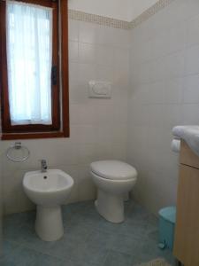 a white bathroom with a toilet and a sink at Cottage LeDune profumi mediterranei vicino al mare in Torre Rinalda