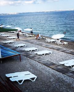 Ada APART&HOTEL في أنطاليا: مجموعة من الكراسي البيضاء والطاولات على الشاطئ