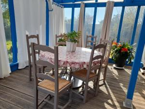 una mesa y sillas en un porche con mesa y ventana en Le chant des oiseaux, en Montmartin-sur-Mer