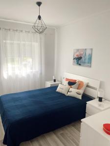um quarto branco com uma cama azul e 2 almofadas em Mima House Al em Aveiro