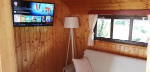 a room with a tv and a bed and a lamp at Wooden house Nela near Plitvice Lakes in Smoljanac