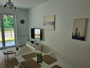 a white living room with a table and a tv at Komfortowy apartament przy lesie in Wejherowo