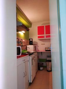 a small kitchen with white appliances and red cabinets at Studio avec balcon amenage a Cauterets in Cauterets